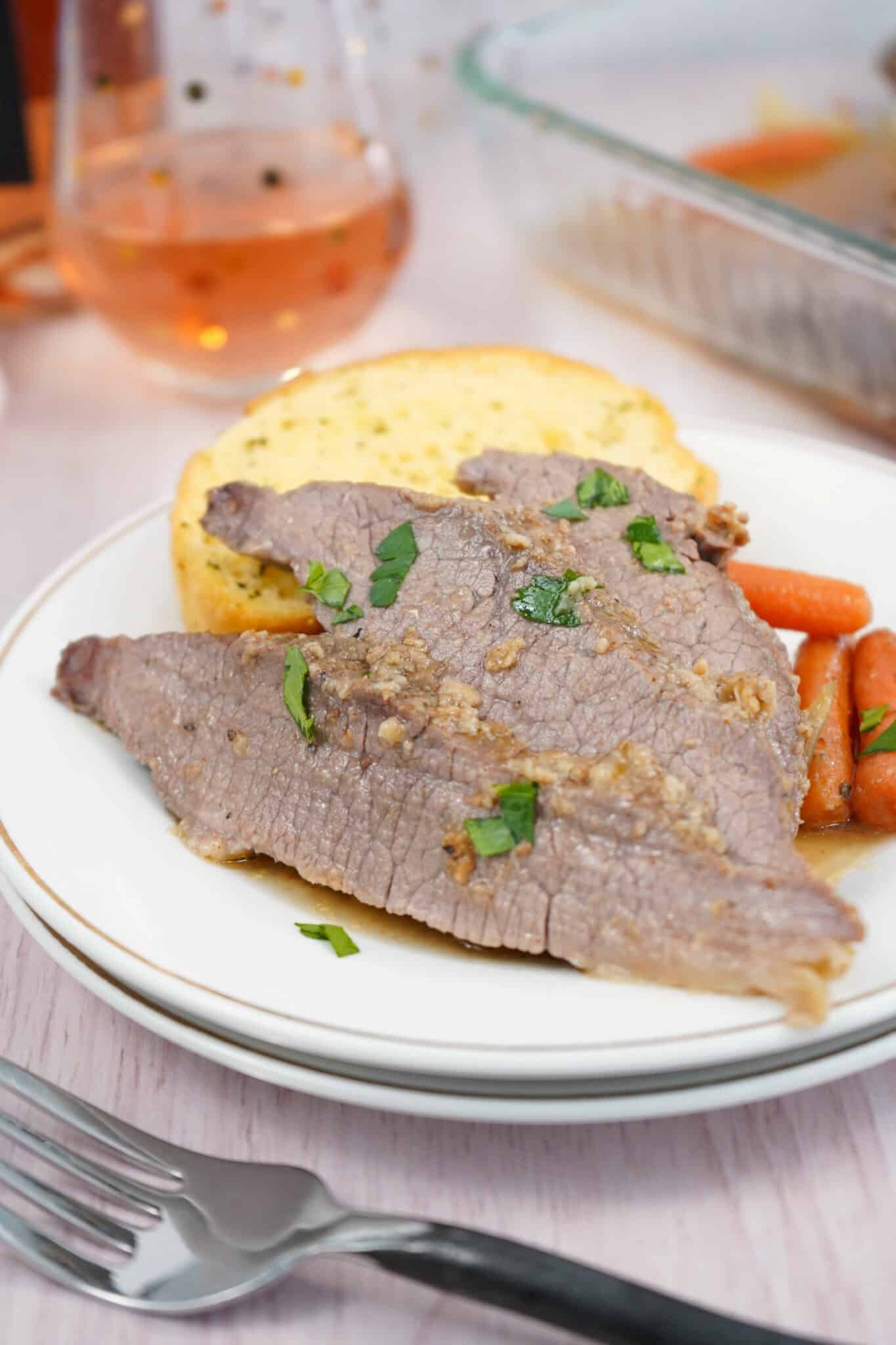 Slices of the oven brisket with the vegetables on a plate.