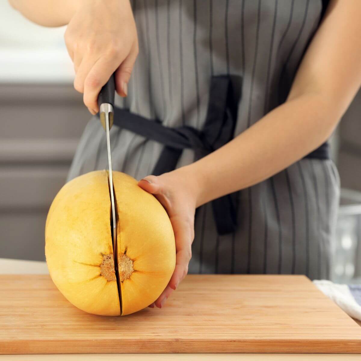 Step one in how to cut a spaghetti squash. Using a knife to cut a squash.