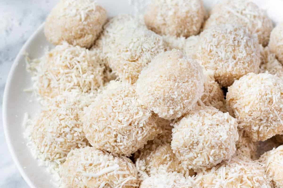 A plate of coconut-covered cheesecake balls arranged tightly together, making delightful Easter treats for kids.