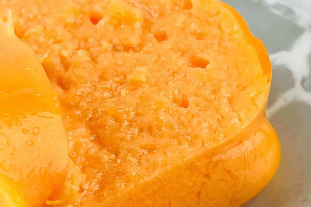 Close-up of a orange jello salad cut in half, revealing its bright orange flesh and smooth texture on a gray surface. This vibrant fruit could be an inspiration for Easter treats for kids, adding a splash of color and flavor to holiday desserts.