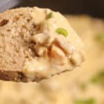 A slice of bread topped with creamy Philly Cheesesteak Dip, garnished with chopped green onions.