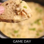 A piece of bread hovers above a pot brimming with creamy Philly Cheesesteak Dip, generously topped with chopped green onions. At the bottom, bold text proudly announces: "Game Day Philly Cheesesteak Dip.