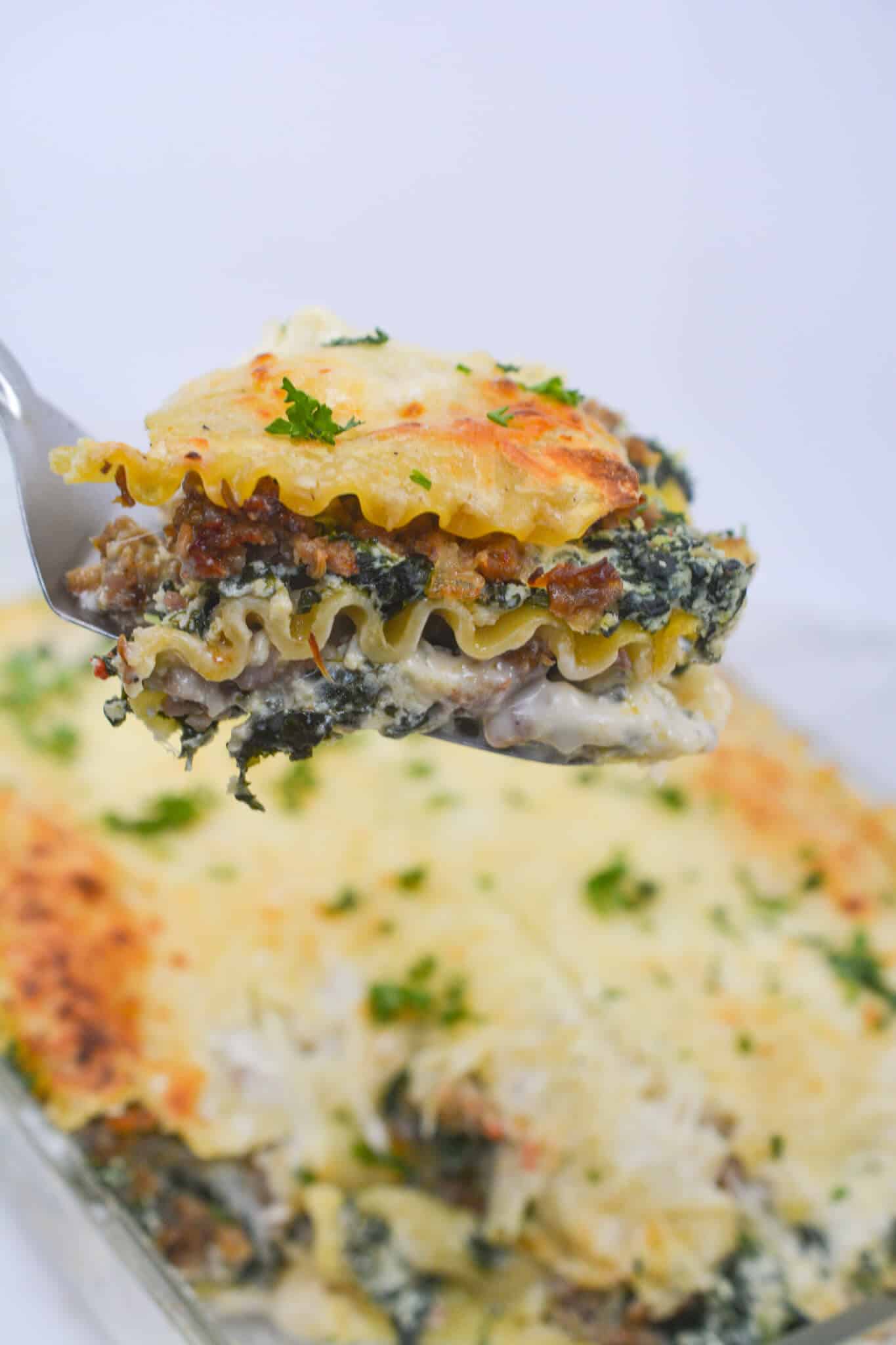 Serving a slice of white lasagna on a fork.