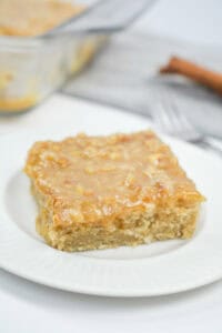A square of vintage oatmeal cake with coconut frosting on a white plate.