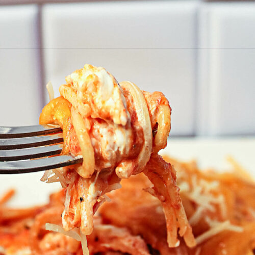 A fork with the spaghetti on it with lots of cheese.