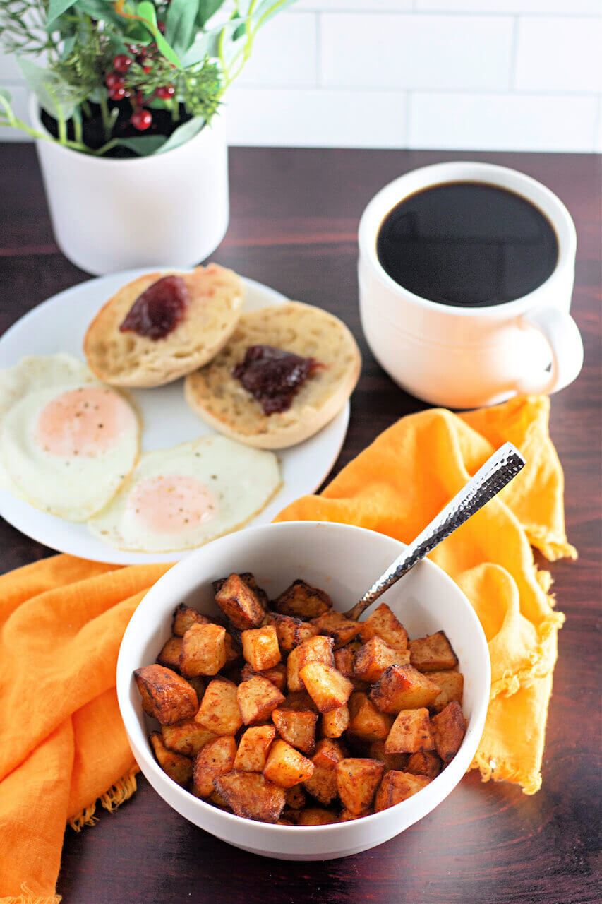 A complete breakfast with eggs, english muffins and coffee along with the the potatoes.