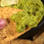 A Tortilla chip covered with guacamole.