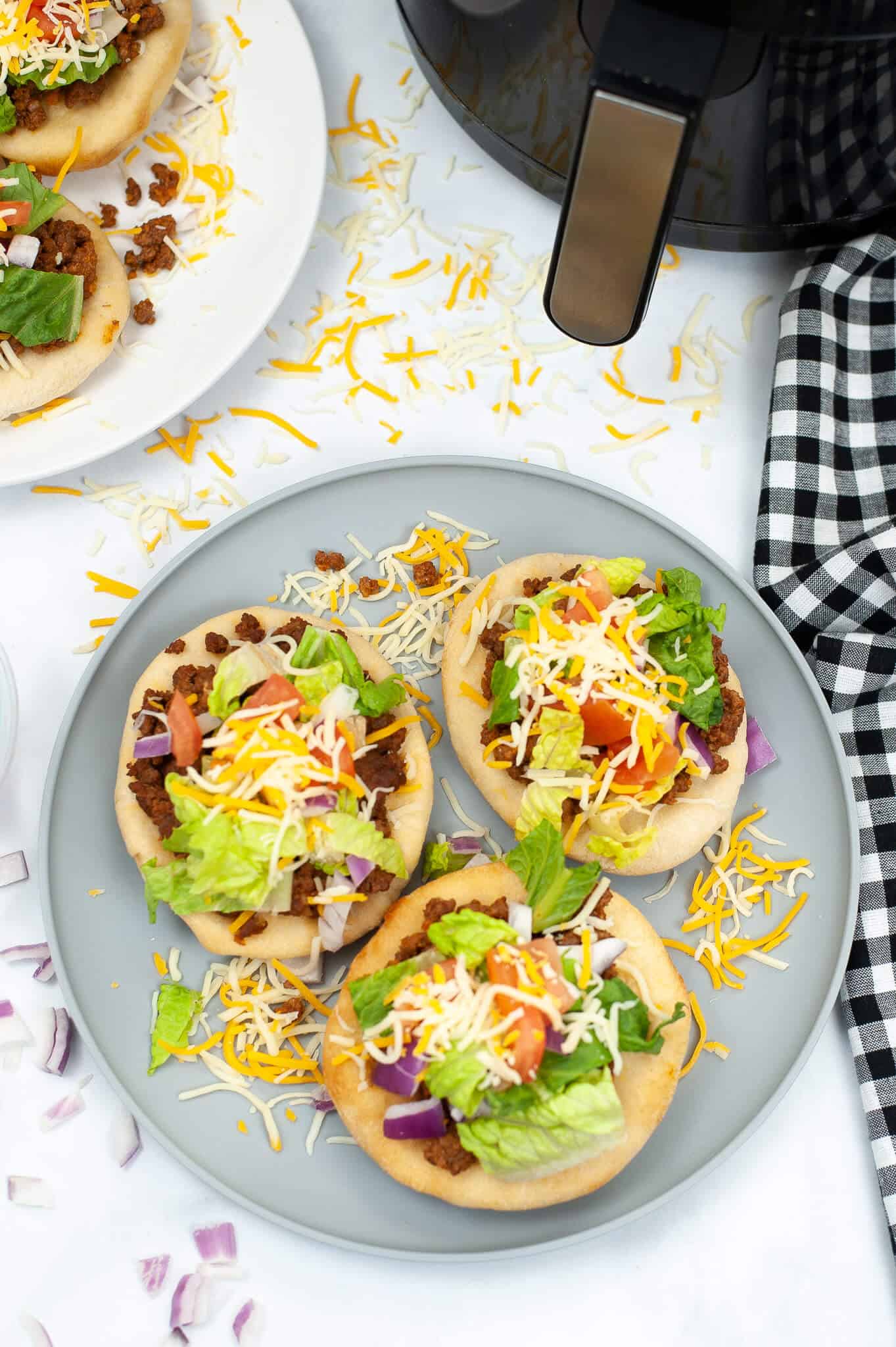 Overhead shot of 3 indian fry bread tacos on a gray plate. 