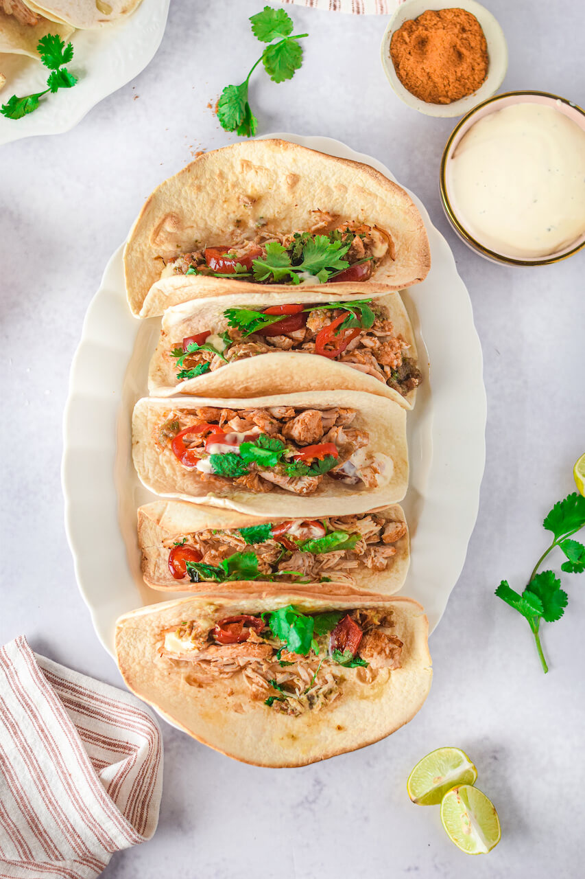 The completed instant pot chicken tacos with fresh herbs on top.