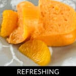 A slice of refreshing Orange Jello Salad with juicy orange segments sits invitingly on a plate.