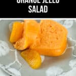 A delightful orange jello salad graces the plate, adorned with vibrant orange slices, all set upon a decorative tablecloth.