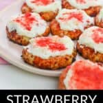 A plate of Strawberry Crunch Cookies topped with white icing and red strawberry crumbles, with the text "Strawberry Crunch Cookies" displayed below.