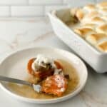 A plate in front of a baking dish filled with more, its golden-brown serving of Sweet Potato Crunch.
