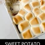 A Sweet Potato Crunch casserole baked to perfection, topped with golden toasted marshmallows in a white dish, with a generous serving scooped out from the corner.