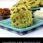 Two green Pistachio Pudding Cookies with chopped pecans sit on a blue plate, next to small bowls of pecans and coconut, with a text label at the bottom.