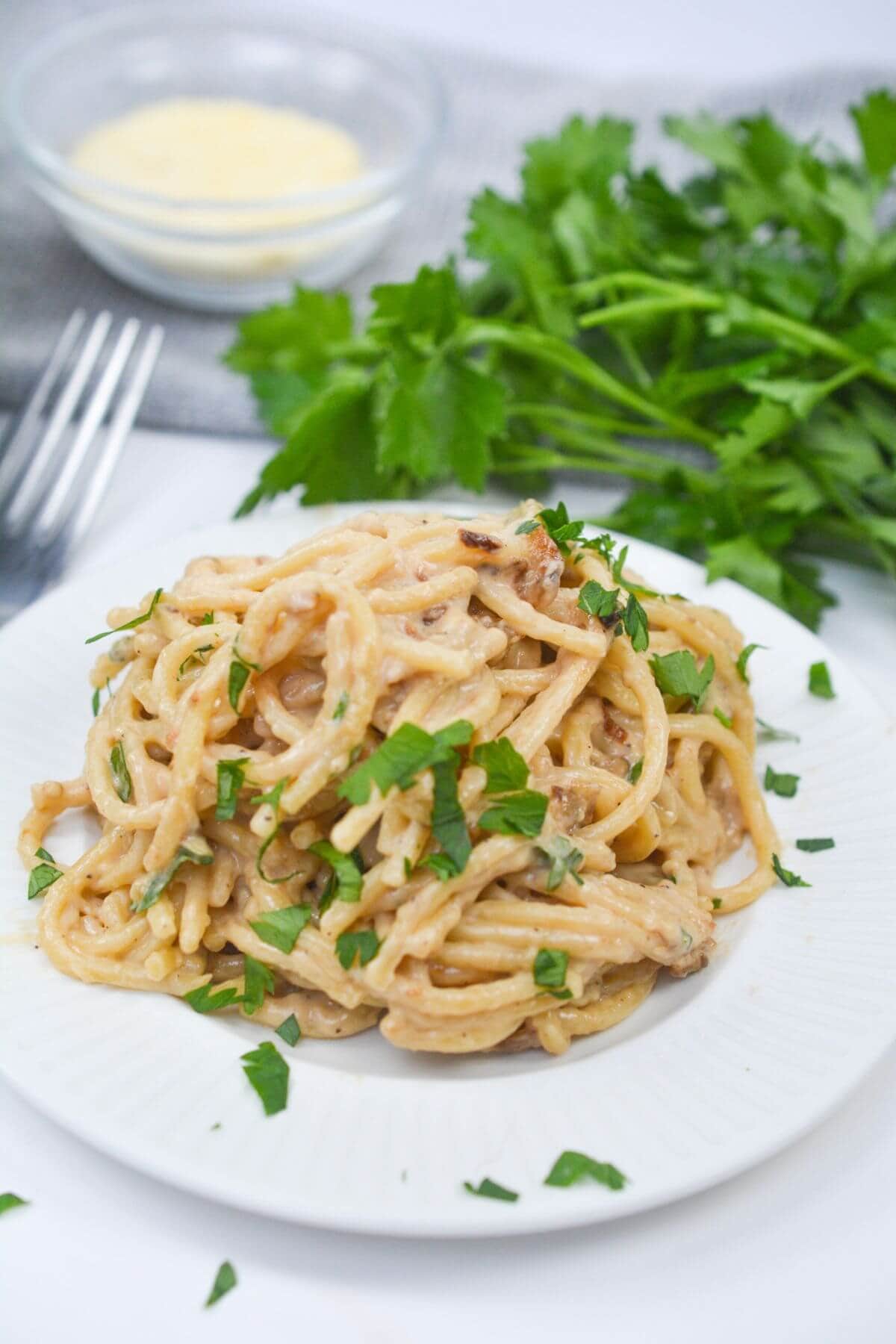 A dish of the dinner on a white plate with herbs on top.