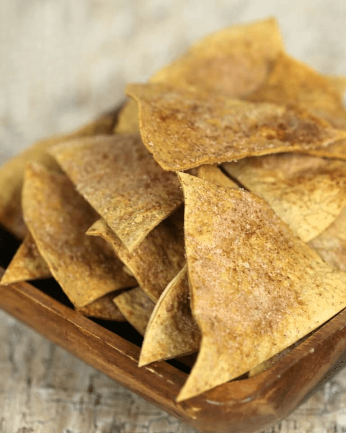 A wooden bowl filled with cinnamon tortilla chips.