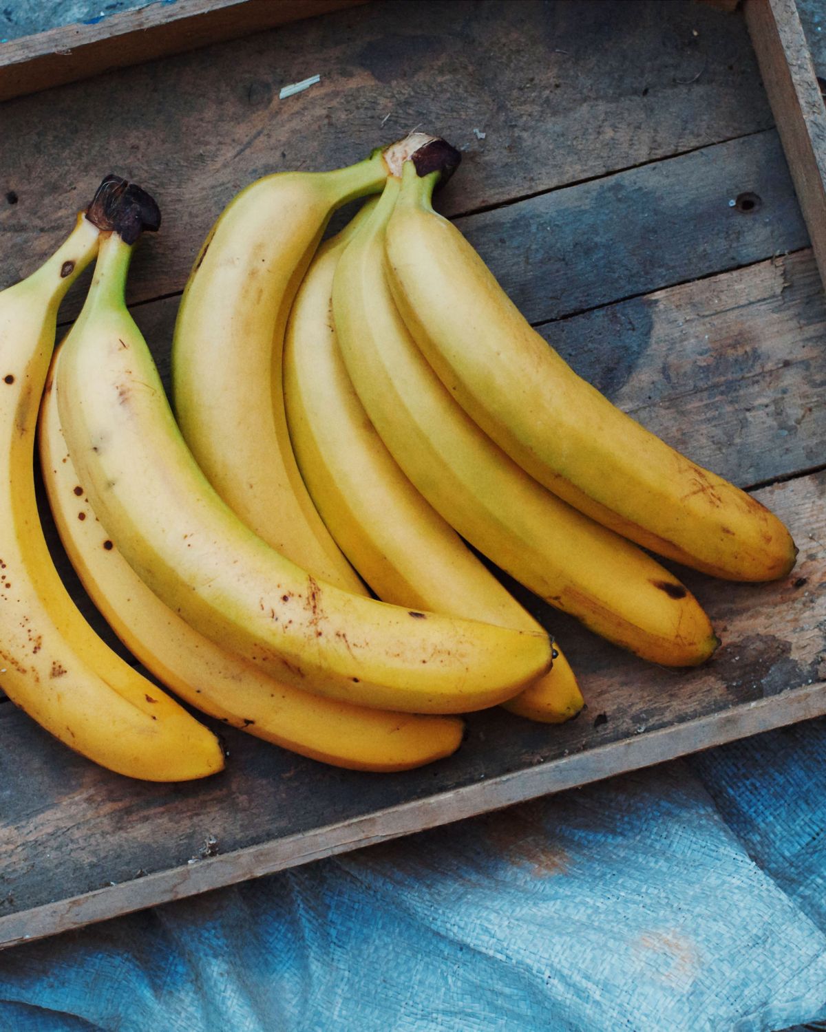 Two bunches of ripe bananas on a wooden tray. 