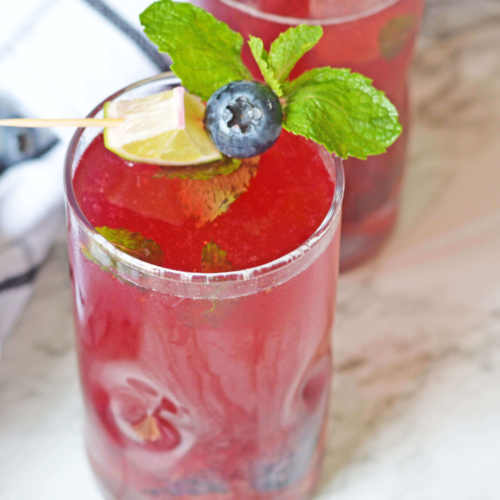 A glass of the blueberry Mojito with mint on top.