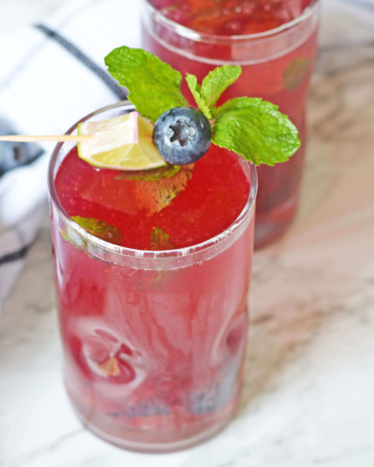A glass of the blueberry Mojito with mint on top.