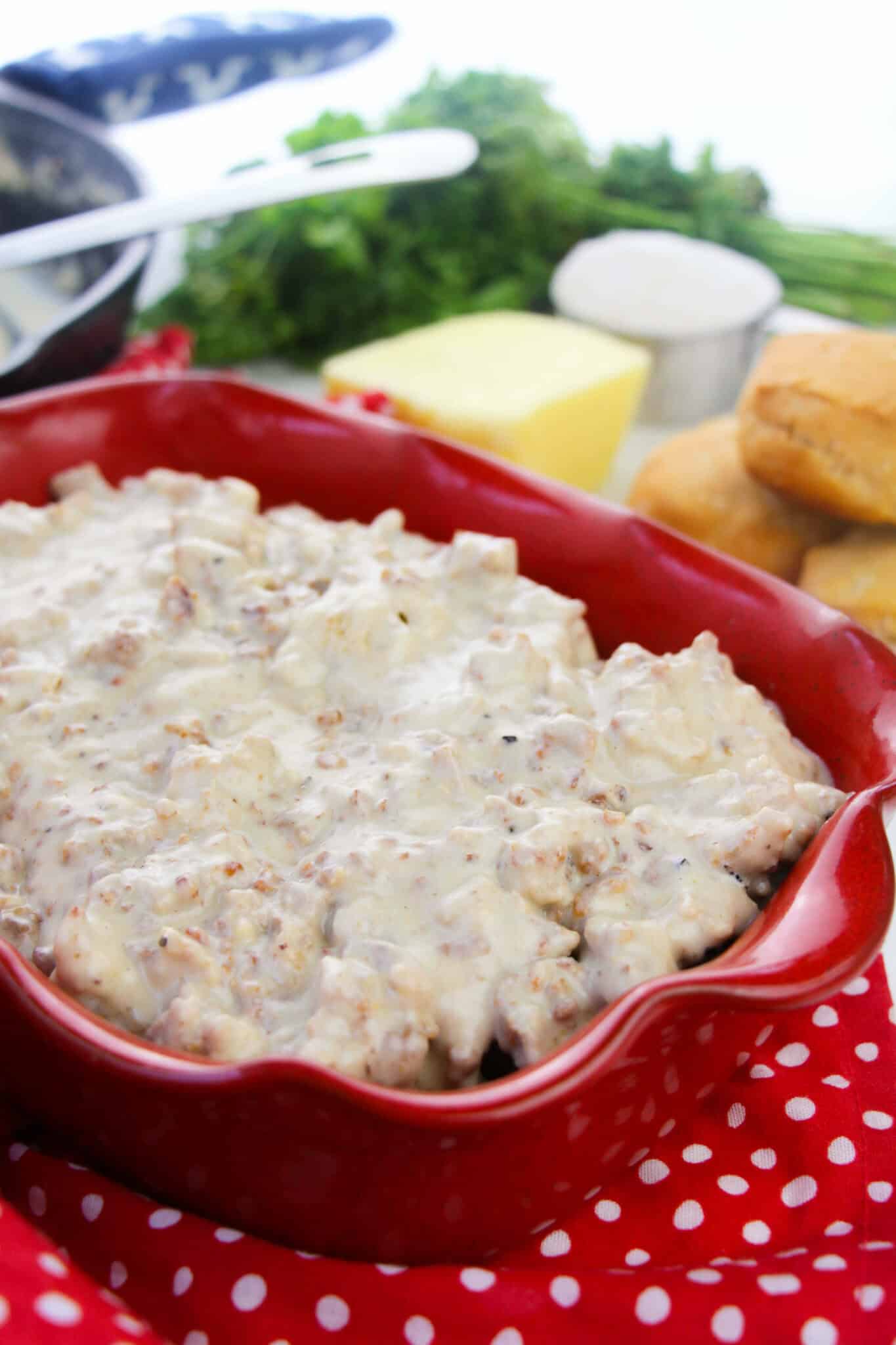 A red serving dish filled with  the country gravy.
