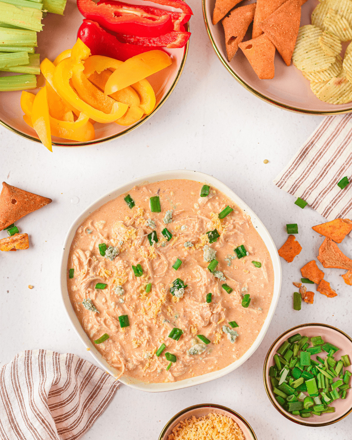 A side of vegetables and chips next to a dish of instant pot buffalo chicken dip.