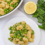 A serving of the gnocchi and a serving dish with the gnocchi with a side of lemon.