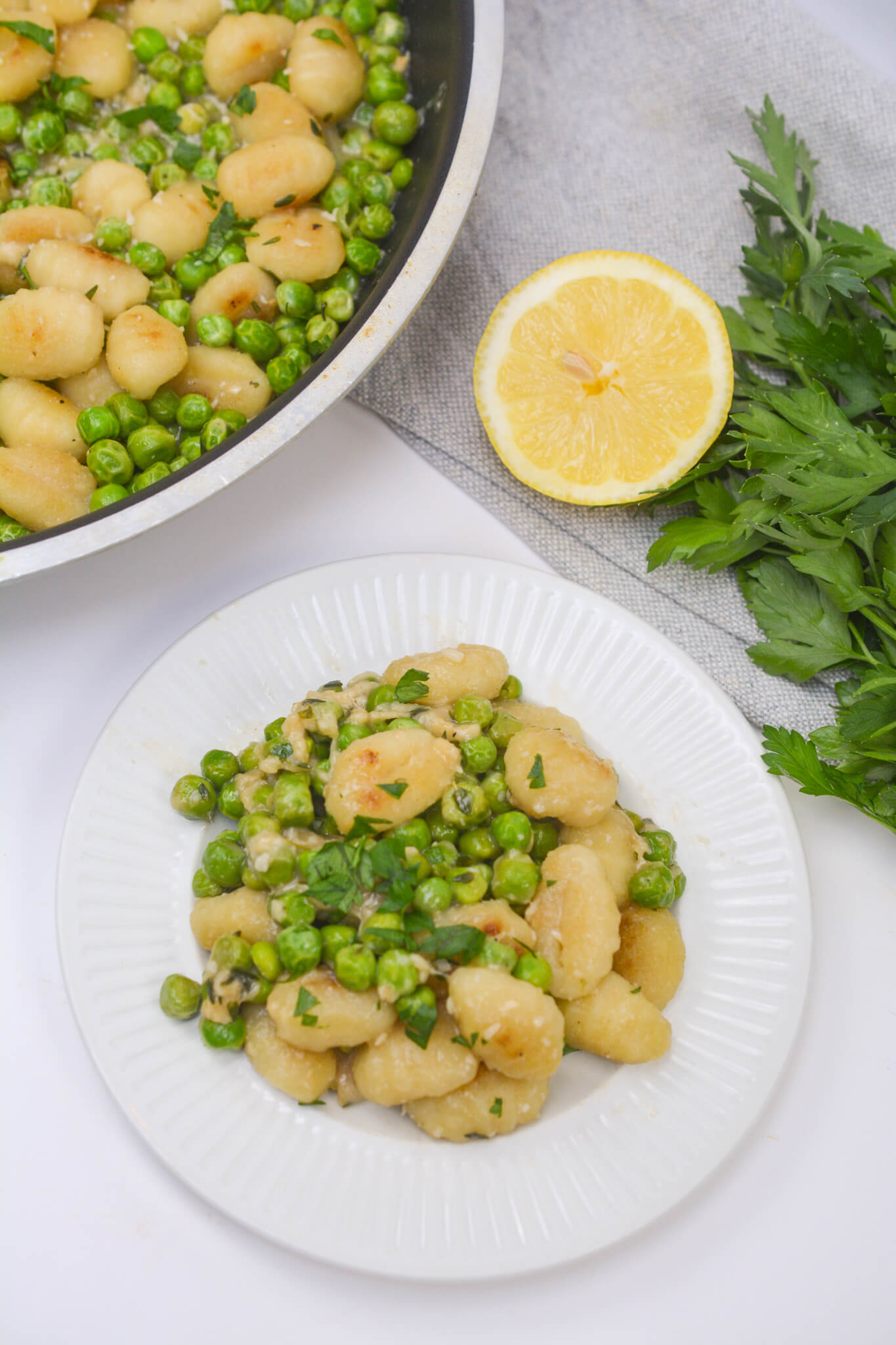 A serving of the gnocchi and a serving dish with the gnocchi with a side of lemon.