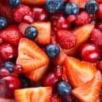 Close-up of a colorful Strawberry Blueberry Salad with fresh sliced strawberries, whole blueberries, raspberries, cherries, and pomegranate seeds.