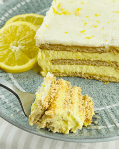 A fork full of the lemon ice box cake with a slice of lemons on it.