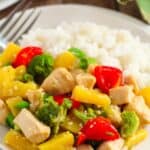 A plate of white rice served with Pineapple Chicken Stir Fry, featuring tender chicken, broccoli, red bell peppers, pineapple chunks, and green onions.