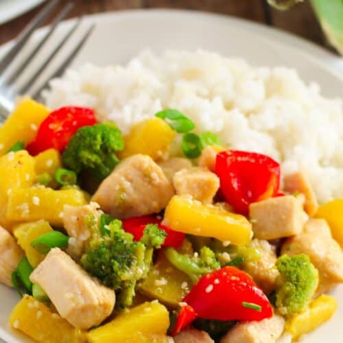 A plate of white rice served with Pineapple Chicken Stir Fry, featuring tender chicken, broccoli, red bell peppers, pineapple chunks, and green onions.