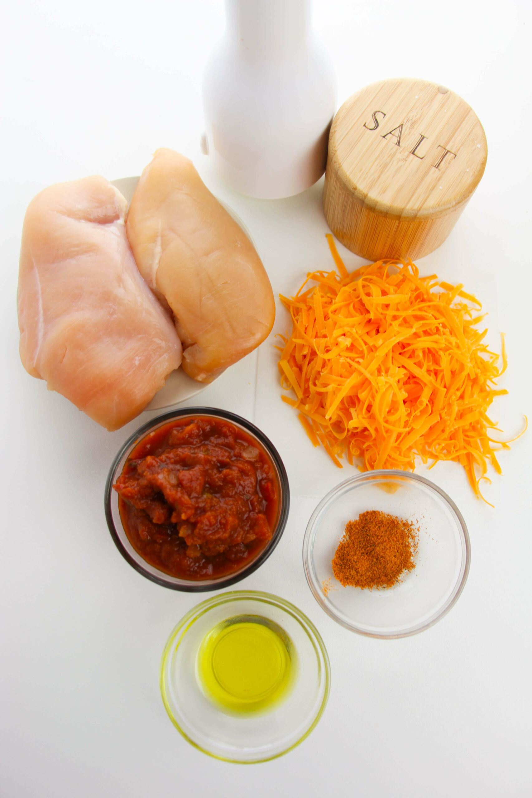 Ingredients to make salsa chicken, including chicken, salsa, cheese and seasoning.