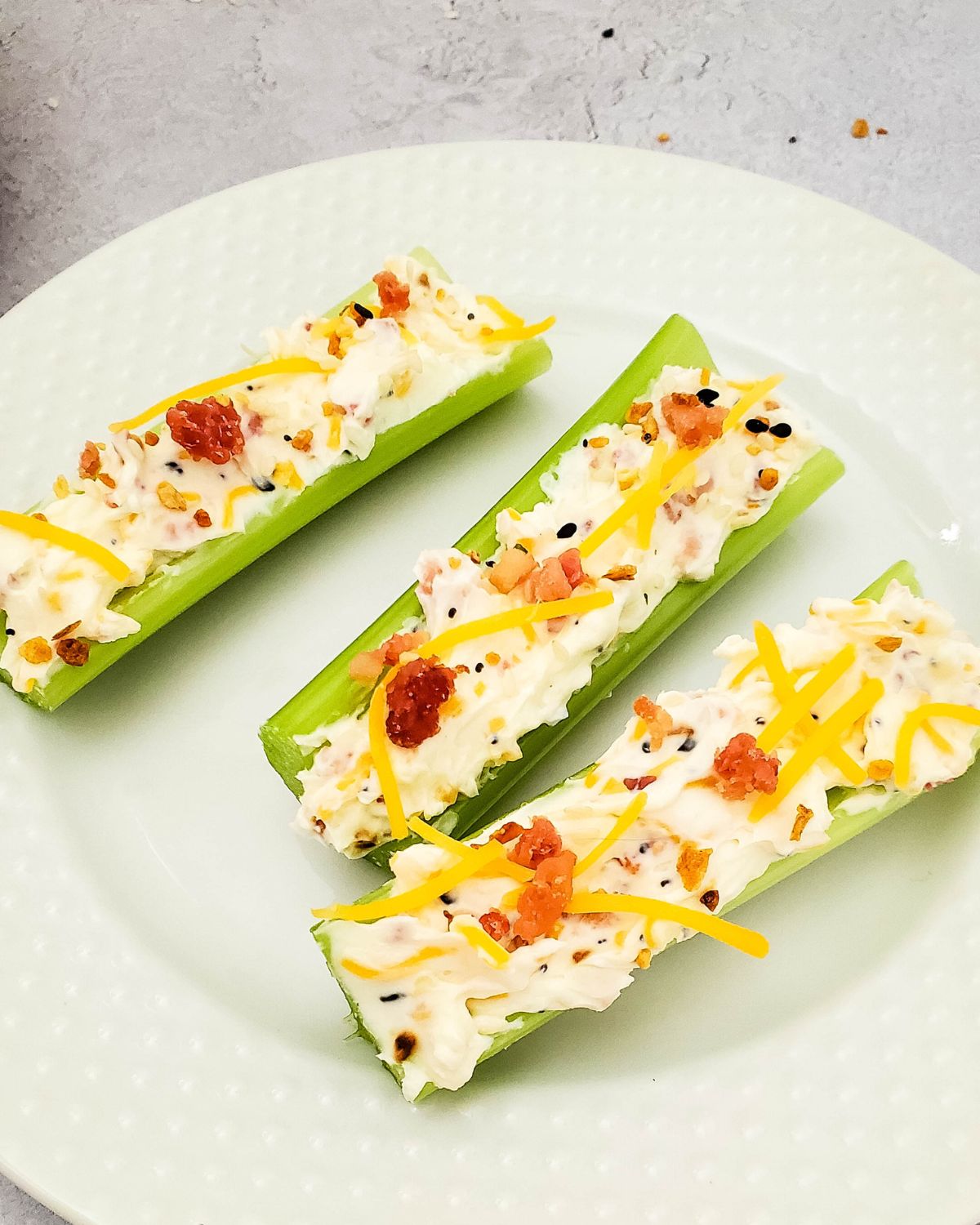 Celery stuffed with cream cheese and bacon a white plate. 