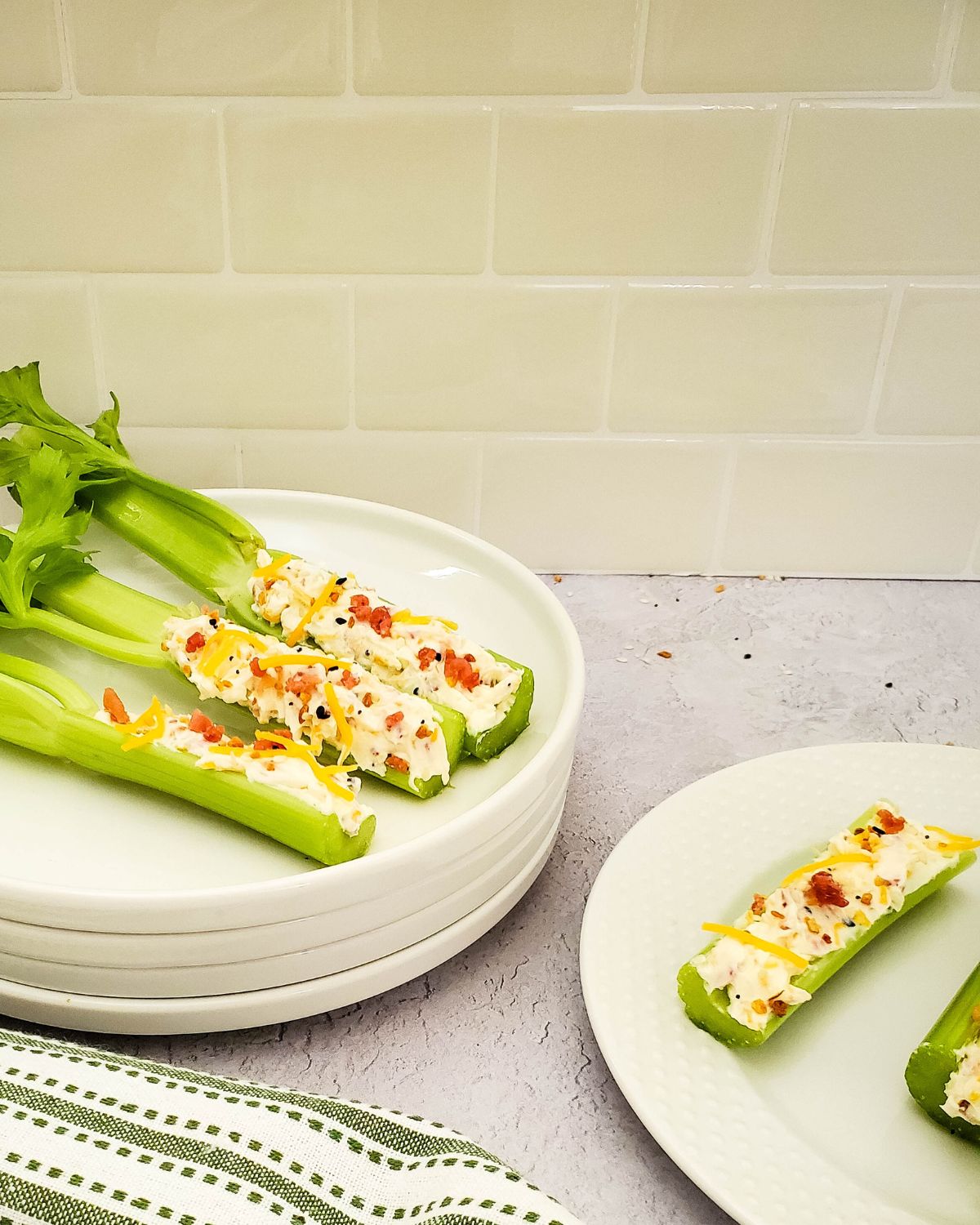 Stuffed celery on a stack of white plates. 