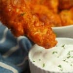 A piece being dipped into a bowl of ranch dressing, with more in the background..