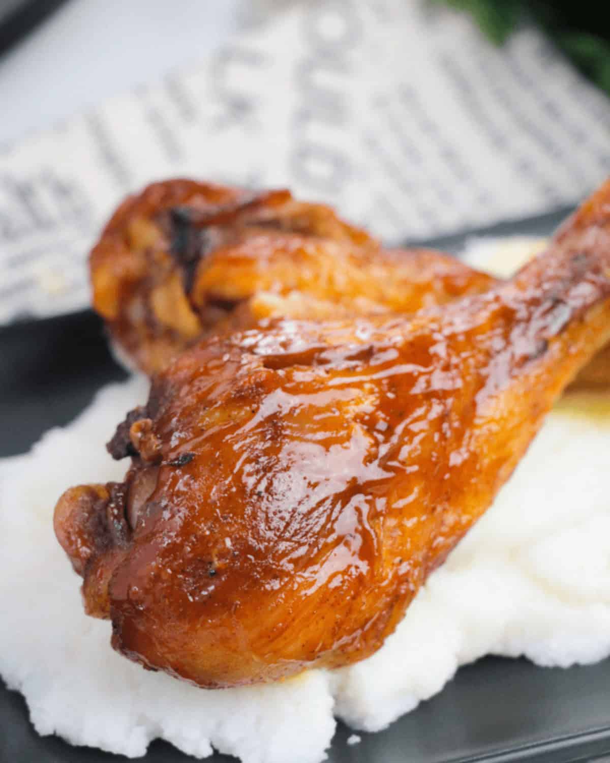 Two BBQ slow cooker drumsticks on top of some mashed potatoes.