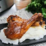 Slow Cooker drumsticks on a black plate.