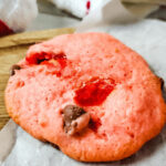 A cherry chip cake mix cookie on parchment paper.