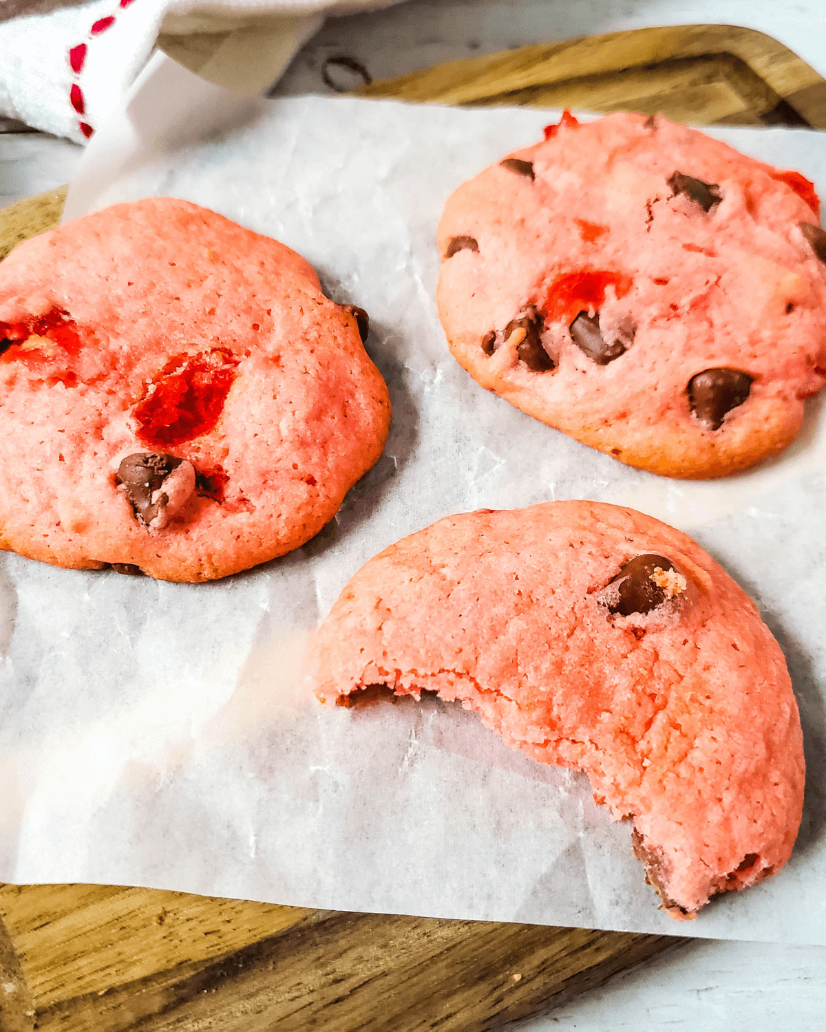 Three cherry chip cake mix cookies on parchment.