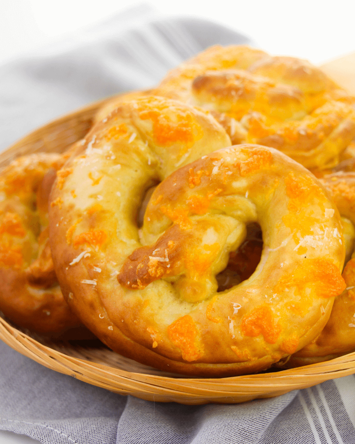 Soft pretzels with cheese stacked on a woodlen plate.