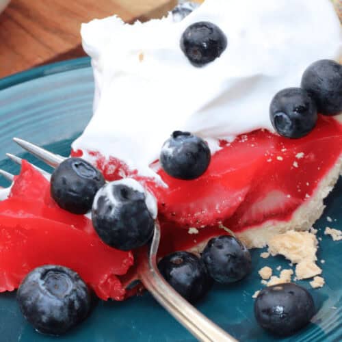 A strawberry Jello pie with whipped cream and blueberries on top.