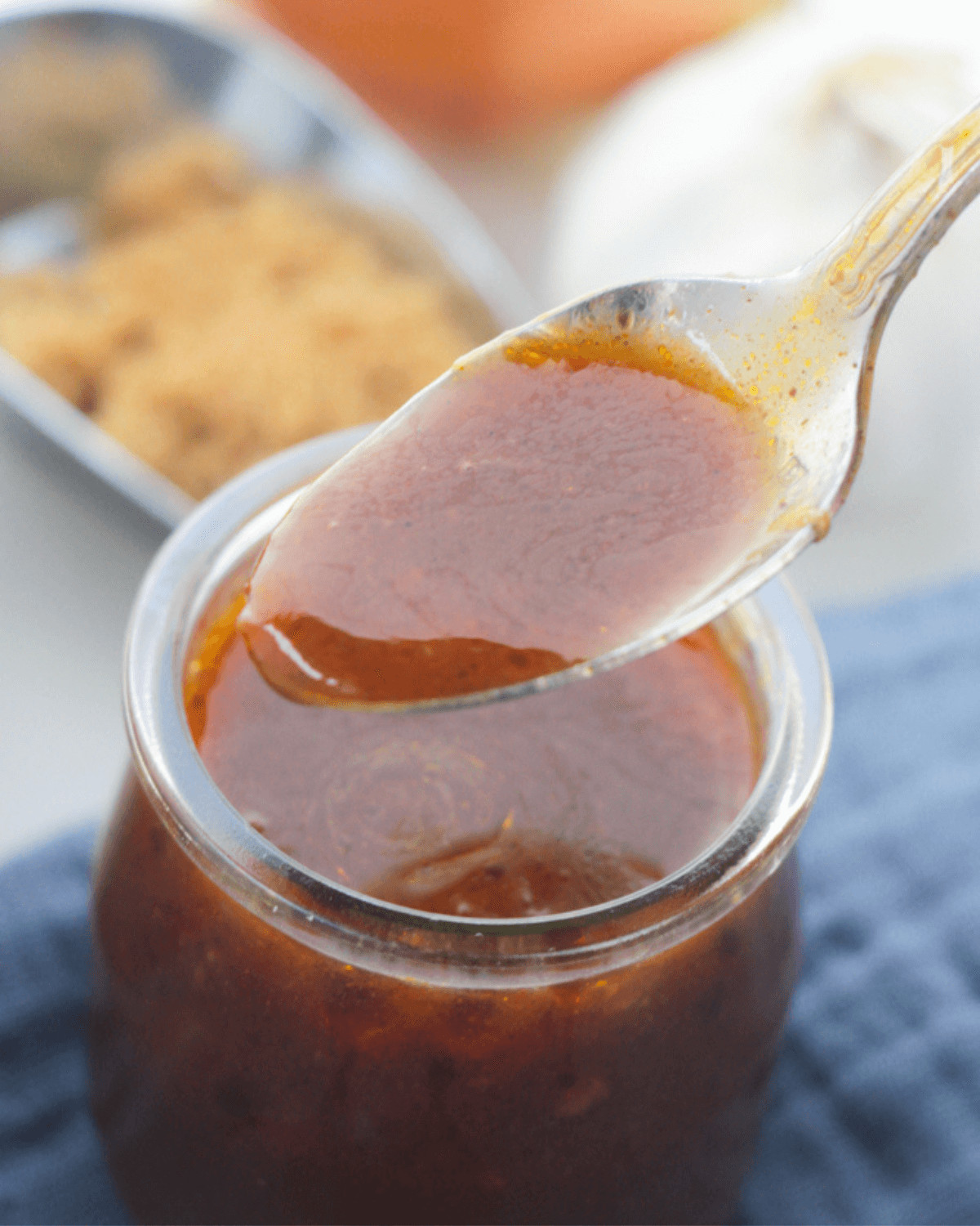 A spoon of the bbq sauce in a glass jar.