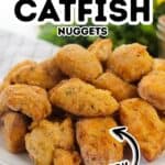 A plate filled with golden brown, crispy Air Fryer Catfish Nuggets sits on a table with text overlay labeling them as crispy.