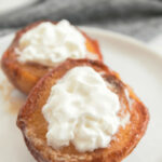 Air fryer peaches on a white plate with whipped cream.