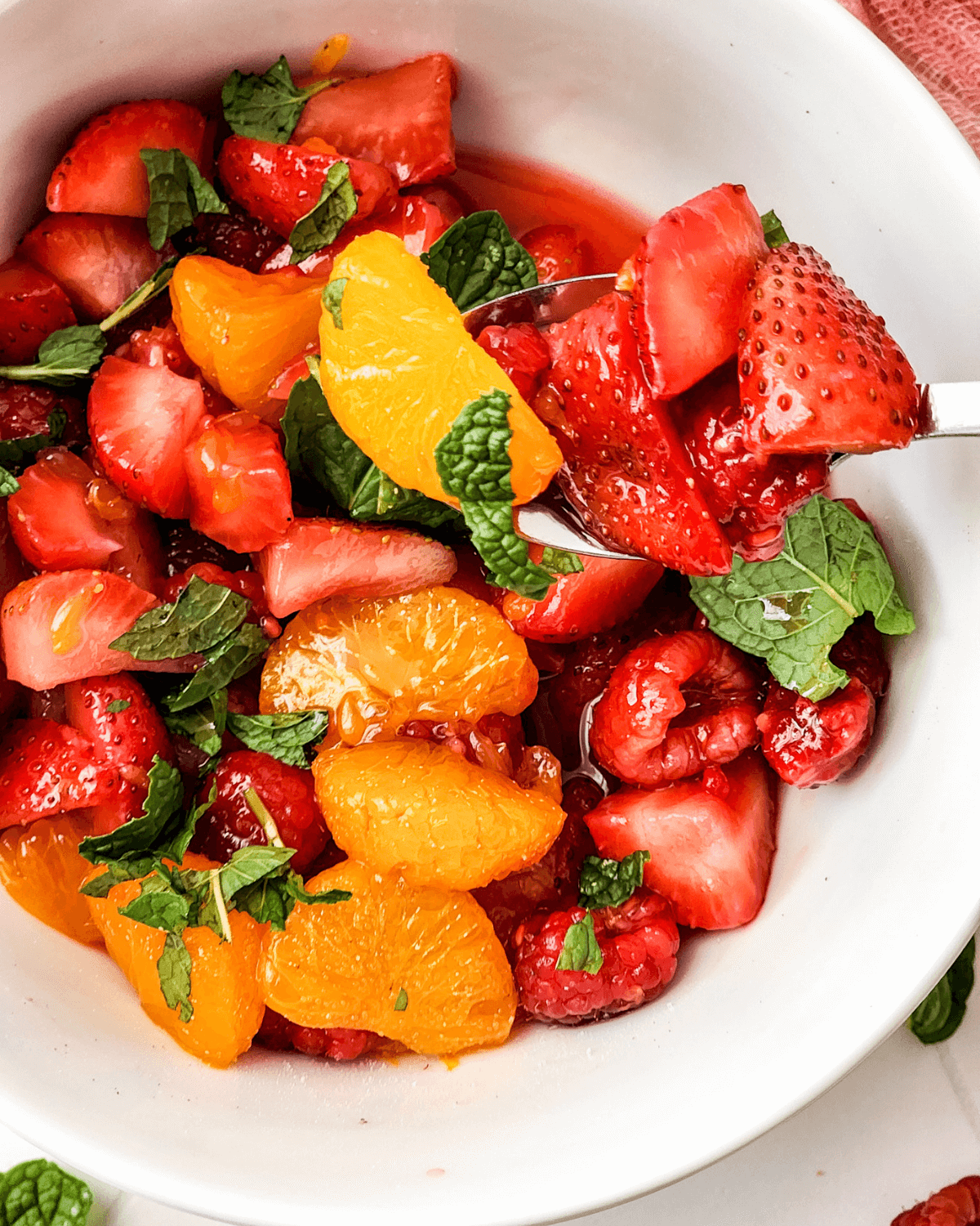 A Berry Breakfast Fruit Salad with Citrus Mint Dressing in a white bowl.