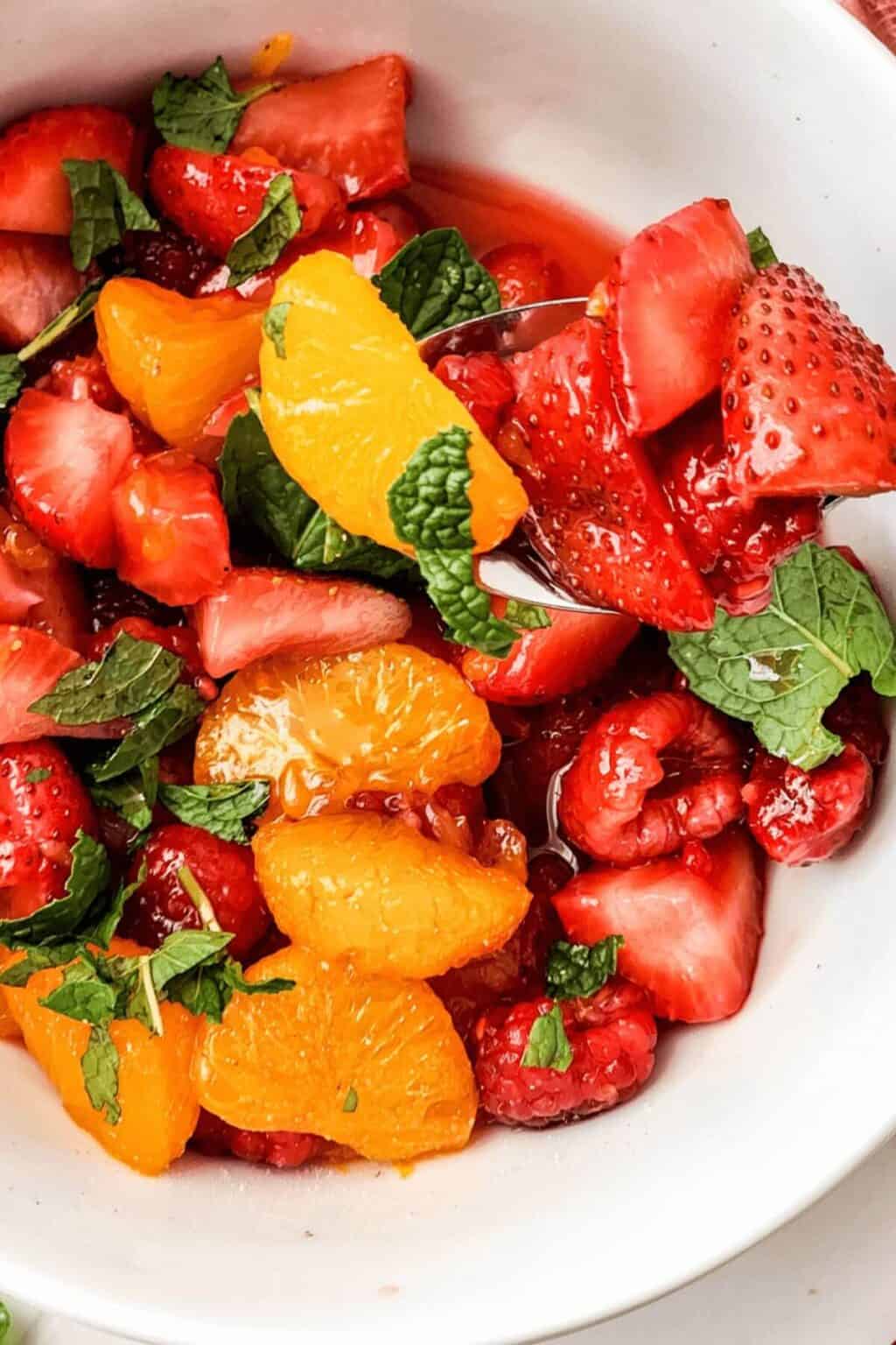 A white bowl of the breakfast fruit salad with honey lime dressing.