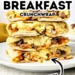 A stack of homemade Breakfast Crunchwraps filled with scrambled eggs, sausage, and cheese sits on a white plate with text overlay reading "Homemade Breakfast Crunchwrap Tasty.
