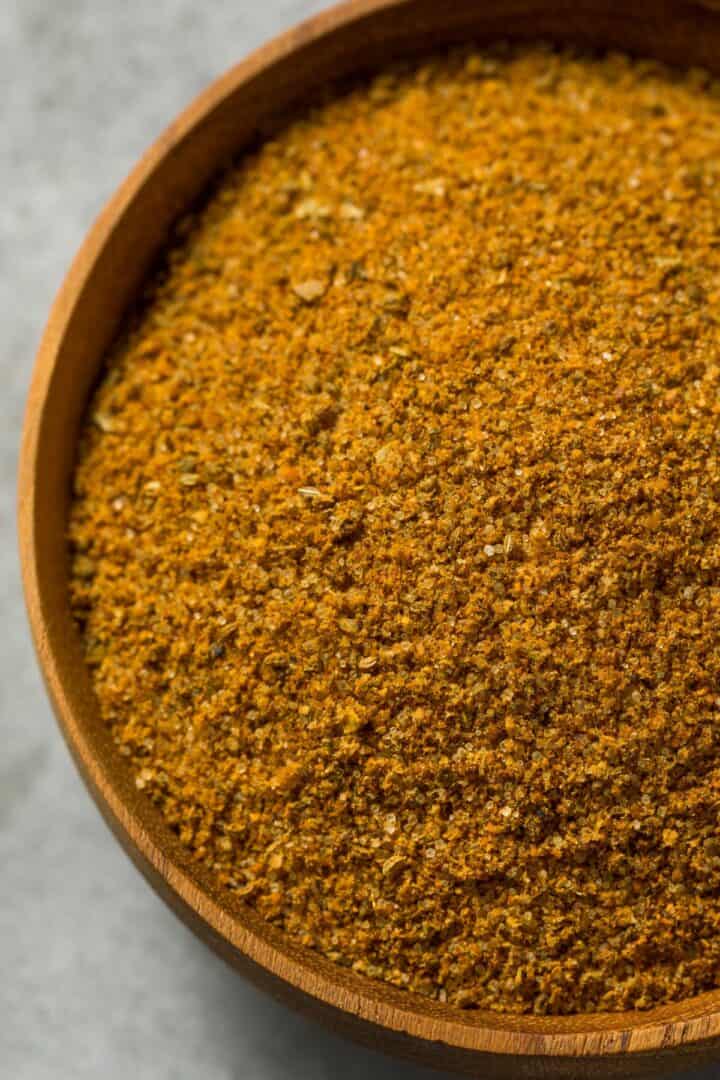 A wooden bowl filled with an orange Cajun seasoning substitute.