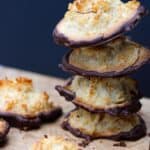 A stack dipped in chocolate, with a few scattered on a wooden surface.